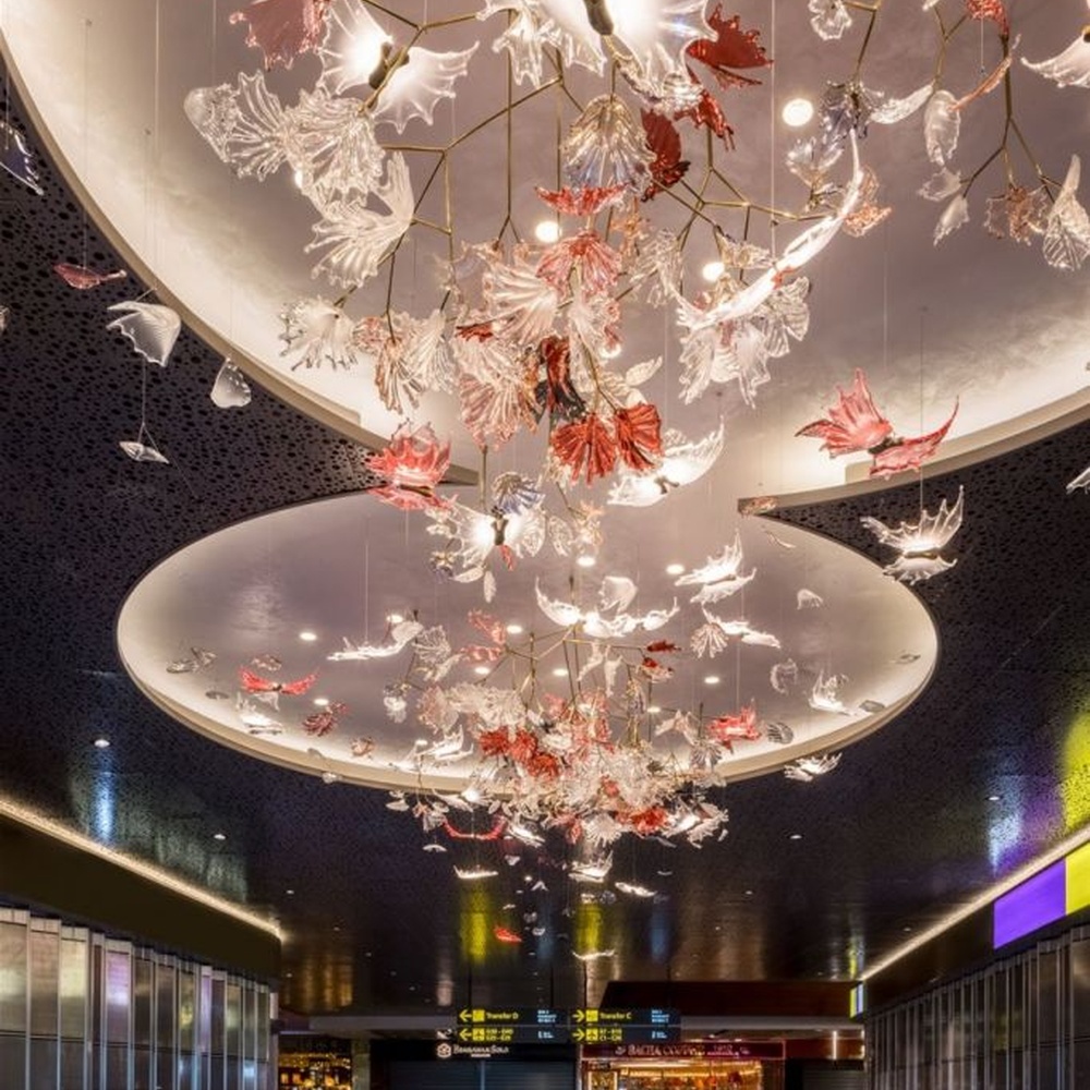 This is a customized artistic flower ceiling chandelier, composed of flower and branch-shaped components made of transparent and red-pink glass/acrylic material, paired with a circular luminous ceiling plate, which has both lighting and artistic decoration functions, suitable for large commercial spaces such as hotel lobbies, banquet halls, and high-end clubs.