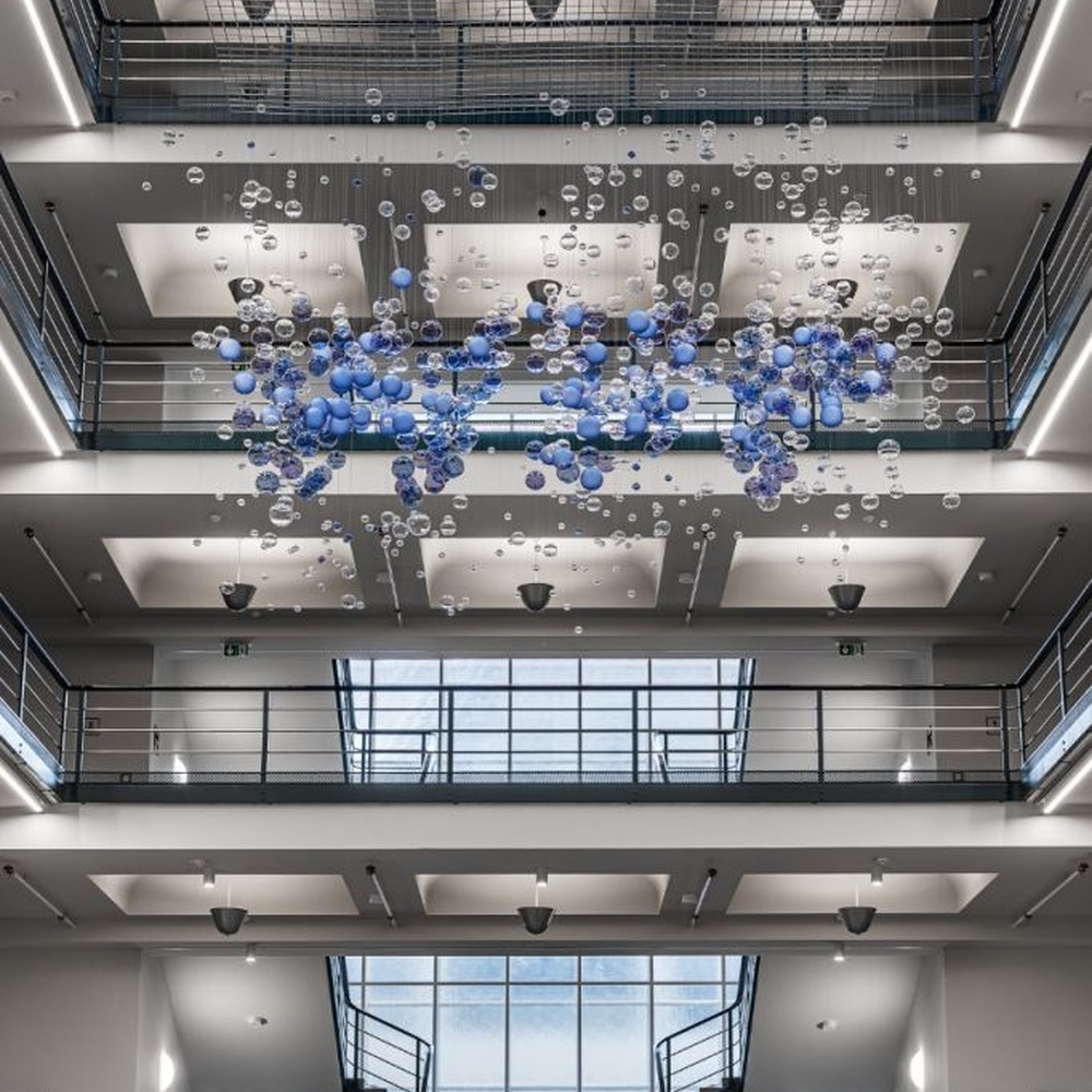 This is a modern art-style suspended bubble installation lamp, composed of transparent and blue-purple gradient spherical elements hung in a staggered manner, with both decorative and lighting functions, ideal for multi-story high-ceiling public spaces such as shopping mall atriums and office building lobbies.