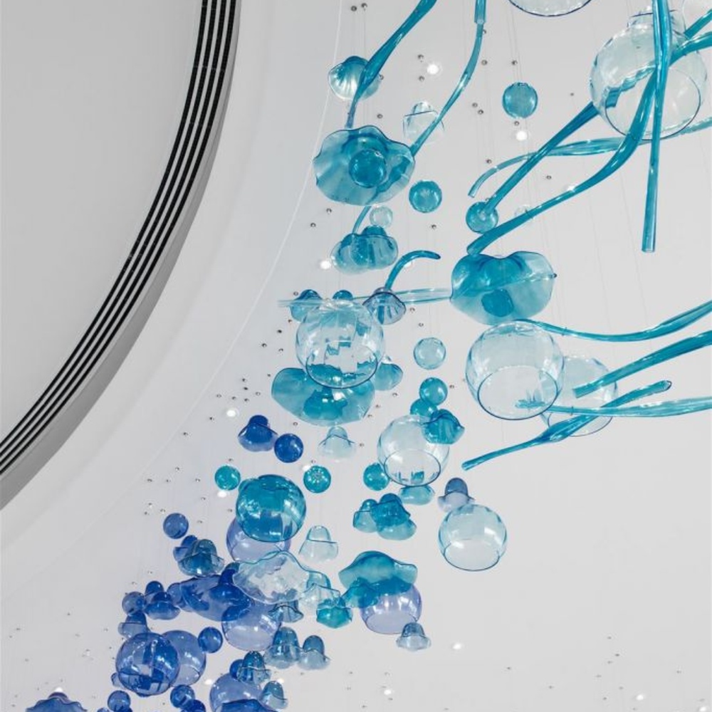 This blue-tone liuli bubble art chandelier is composed of gradient blue and transparent glass bubbles intertwined with metal lines, presenting a dynamic shape like marine plankton. Light refracts through the liuli to emit a transparent and soft halo, serving both lighting and installation art purposes, suitable for high-end commercial spaces such as hotel lobbies and art exhibition halls.