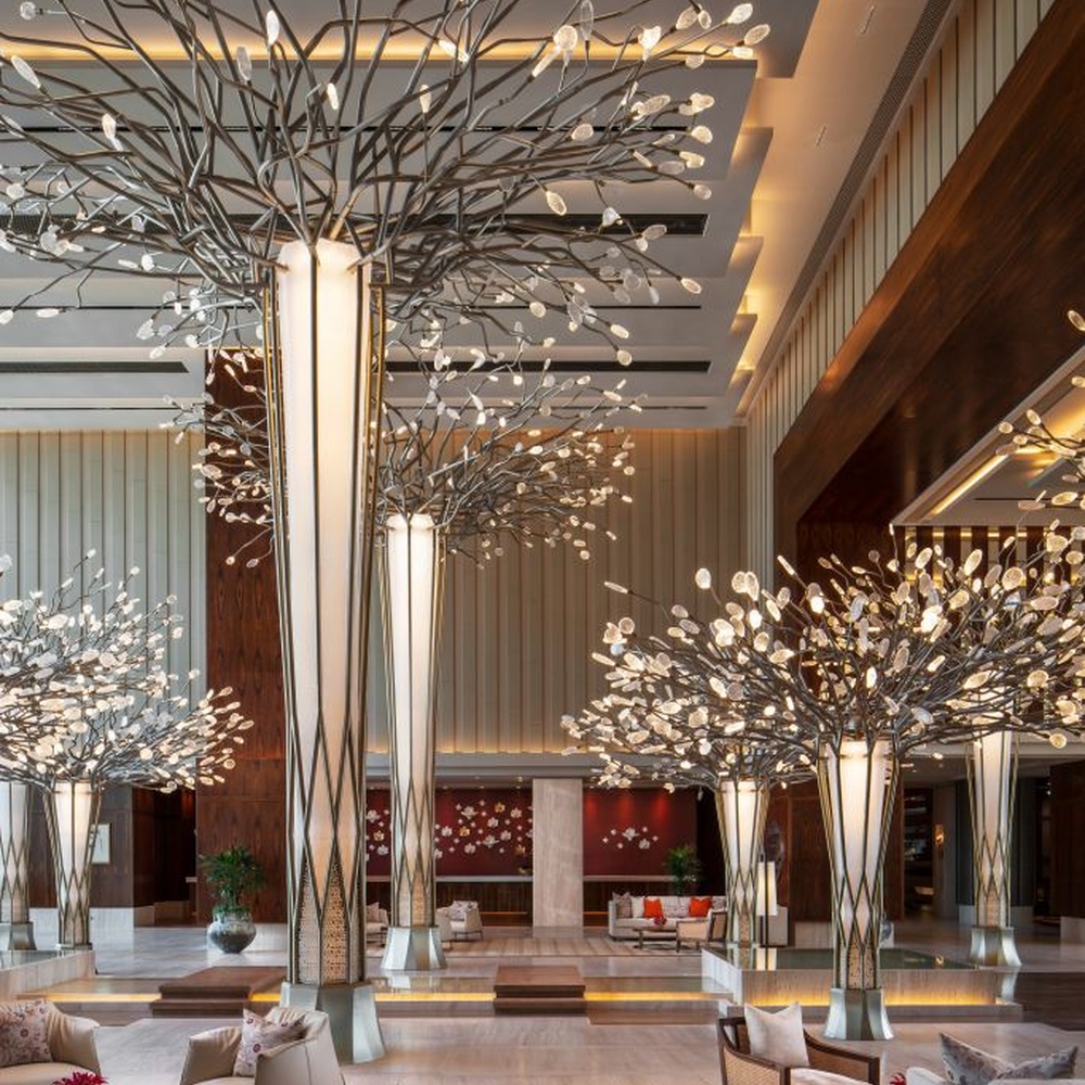 This new Chinese artistic tree-shaped chandelier features a metal branch frame paired with transparent light-emitting leaf-shaped ornaments, presenting a visual effect of blooming flower trees, serving both lighting and decorative purposes, suitable for large spaces such as hotel lobbies and high-end clubs.