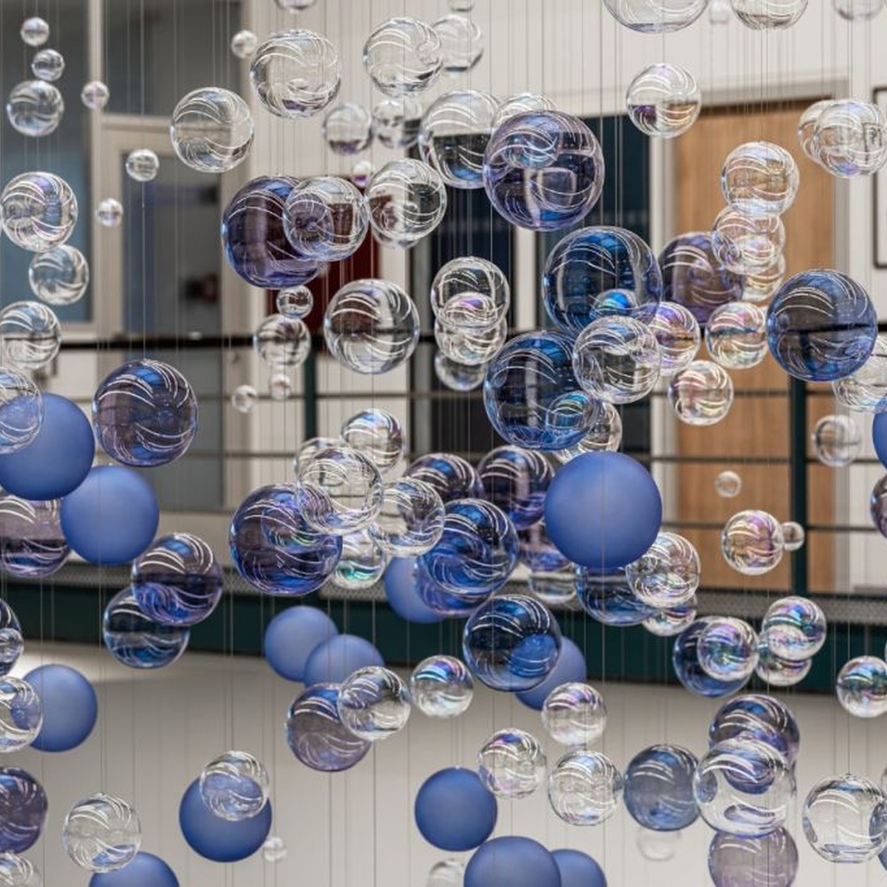 This is a modern art-style suspended bubble installation lamp, composed of transparent and blue-purple gradient spherical elements hung in a staggered manner, with both decorative and lighting functions, ideal for multi-story high-ceiling public spaces such as shopping mall atriums and office building lobbies.