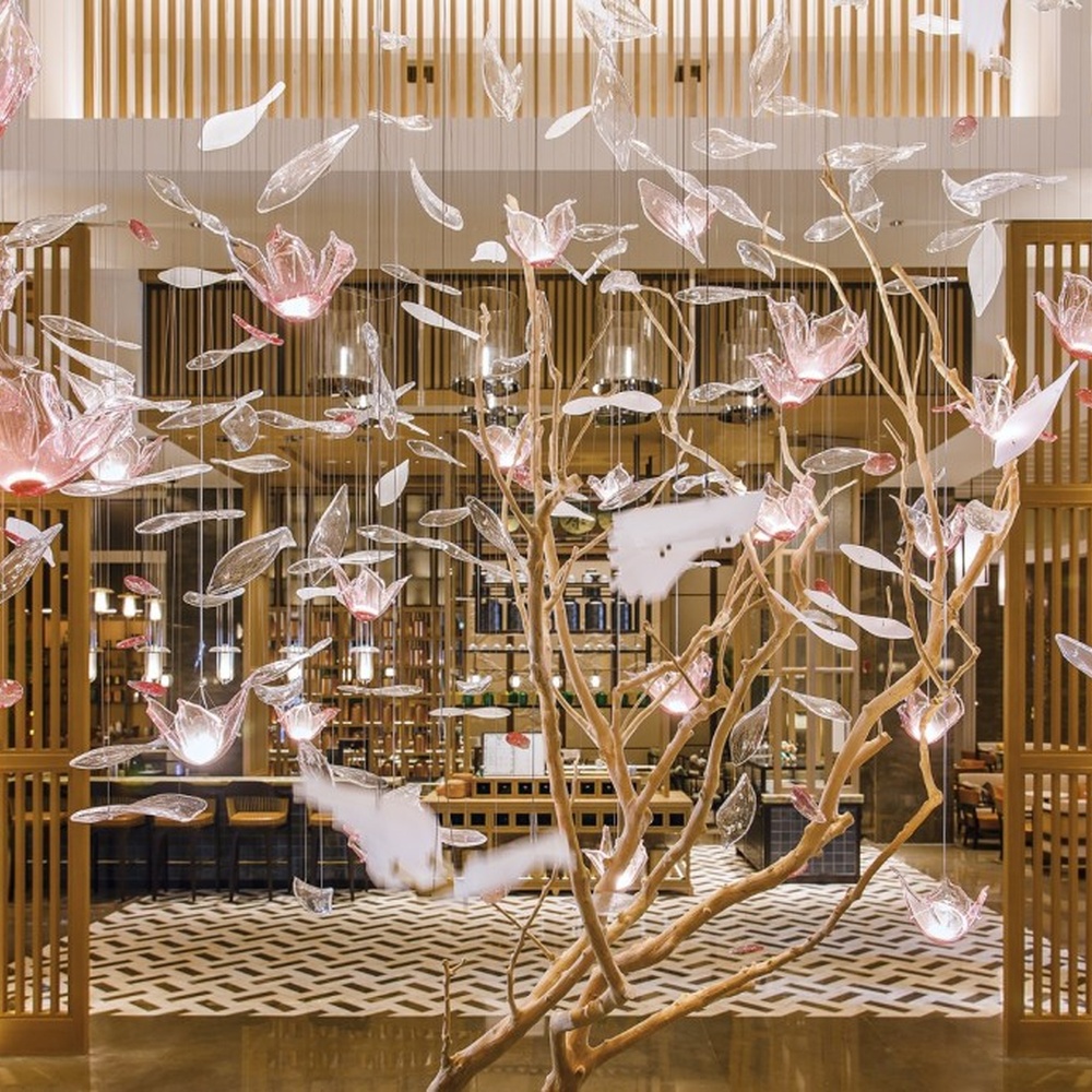 This is an art-installation style tree-shaped chandelier, with a simulated branch as the main structure, paired with transparent and pink-white gradient leaf-shaped luminous components, which has both artistic decoration and soft lighting functions, suitable for large commercial spaces such as hotel lobbies, high-end clubs, and art exhibition halls.