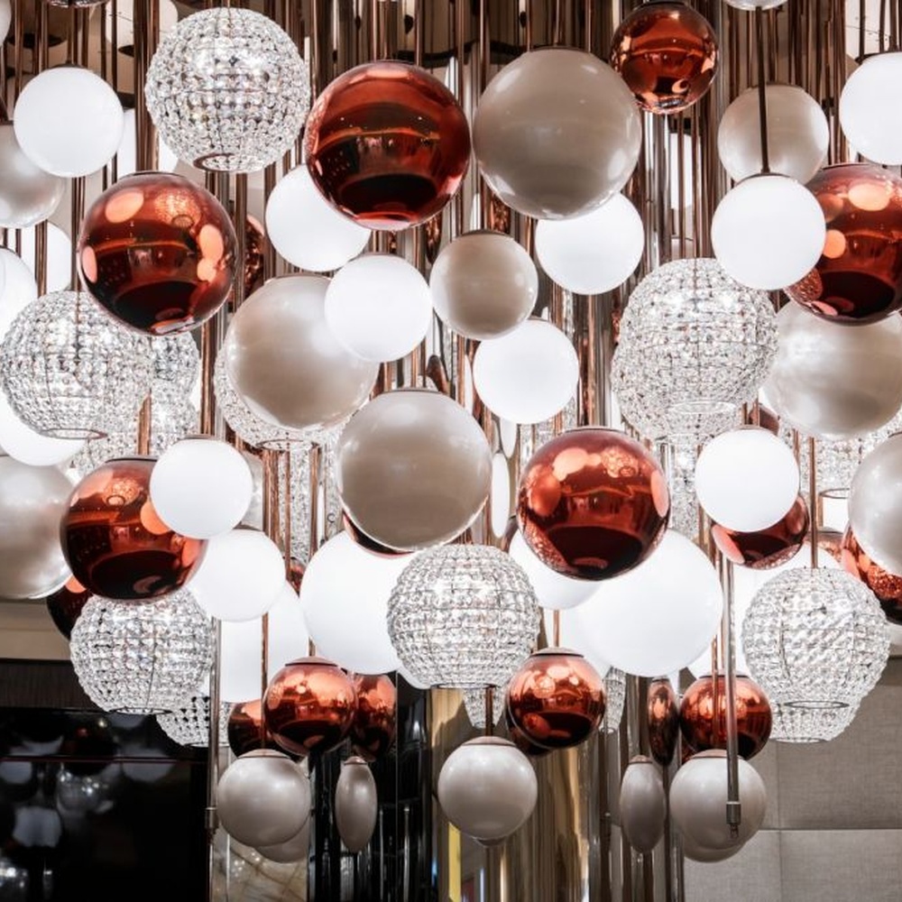This is a modern luxury style cluster spherical chandelier, composed of red, white and silver glass balls arranged in a staggered manner, embedded in a circular ceiling structure, which has both lighting and artistic decoration functions, suitable for large commercial spaces such as hotel lobbies, shopping mall atriums, and high-end clubs.