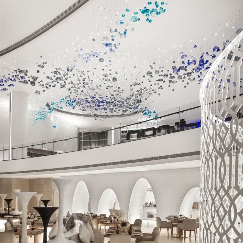 This blue-tone liuli bubble art chandelier is composed of gradient blue and transparent glass bubbles intertwined with metal lines, presenting a dynamic shape like marine plankton. Light refracts through the liuli to emit a transparent and soft halo, serving both lighting and installation art purposes, suitable for high-end commercial spaces such as hotel lobbies and art exhibition halls.