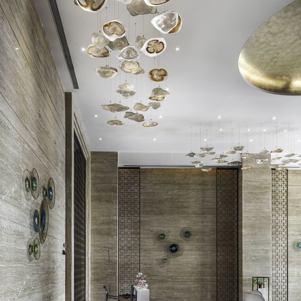 This modern art cloud-slice chandelier consists of irregular transparent and gold cloud-shaped ornaments hung staggered, as light as floating clouds. Light passes through the ornaments to emit a soft and transparent halo, serving both lighting and decorative purposes, suitable for high-end commercial spaces such as luxury sales offices and clubs.