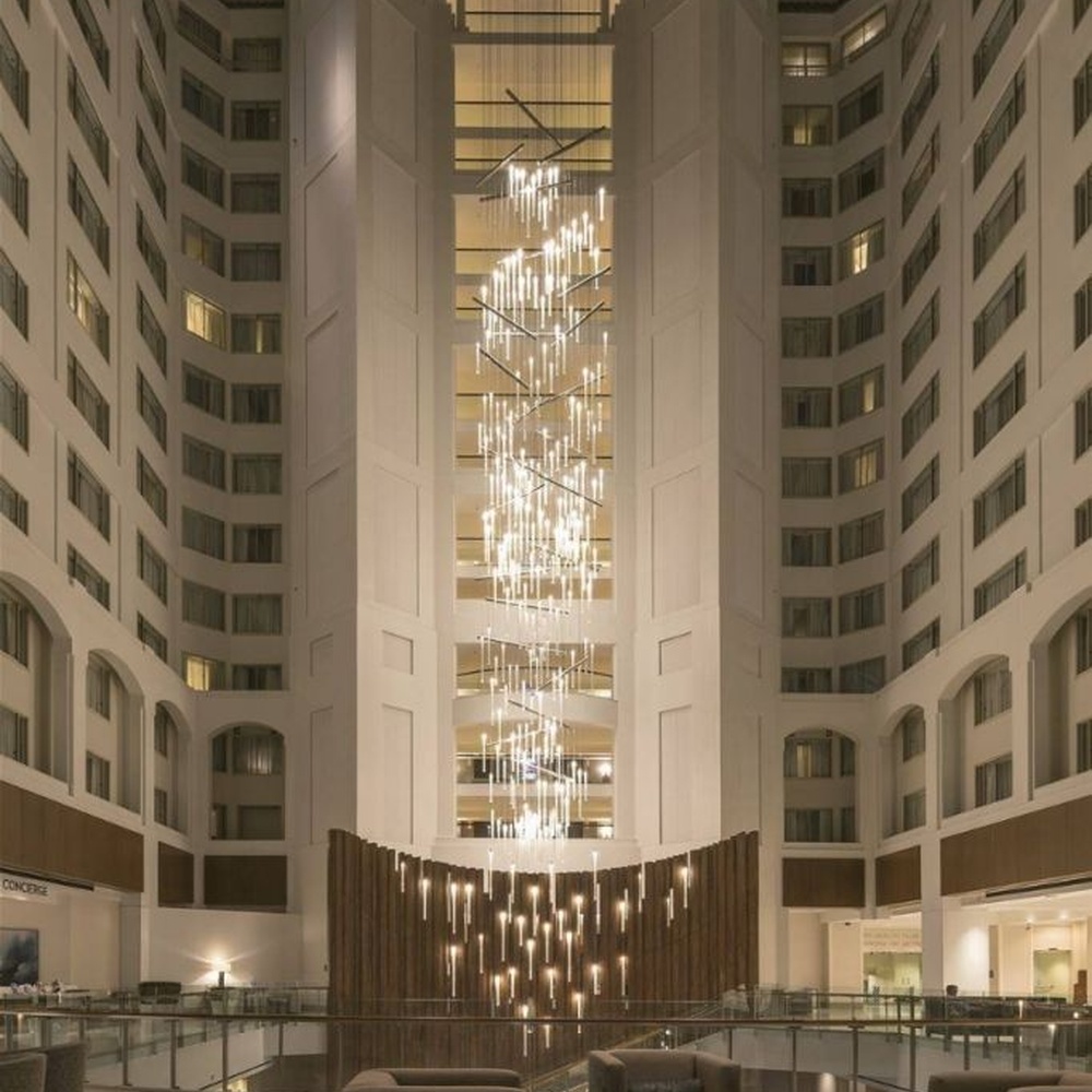 This modern light rain art lighting group consists of a large number of slender linear light strips hanging vertically, creating a "pouring light rain" visual effect with a wooden background wall, serving both lighting and installation art purposes, suitable for high-ceiling commercial spaces such as hotel lobbies and convention centers.