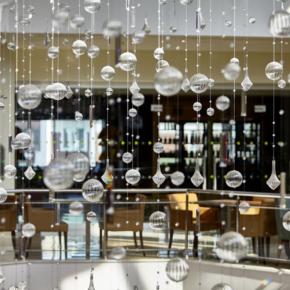 This large artistic bubble chandelier is composed of a large number of transparent glass bubble balls hung in a staggered manner by metal wires, presenting a visual effect like scattered starry sky. The light refracts through the bubbles to emit soft and transparent light spots, serving both lighting and decorative purposes, suitable for high-ceiling commercial spaces such as hotel lobbies and shopping mall atriums.