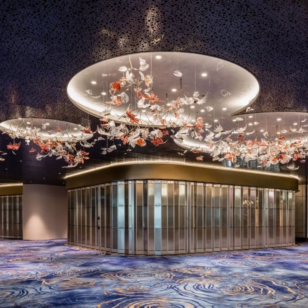This is a customized artistic flower ceiling chandelier, composed of flower and branch-shaped components made of transparent and red-pink glass/acrylic material, paired with a circular luminous ceiling plate, which has both lighting and artistic decoration functions, suitable for large commercial spaces such as hotel lobbies, banquet halls, and high-end clubs.