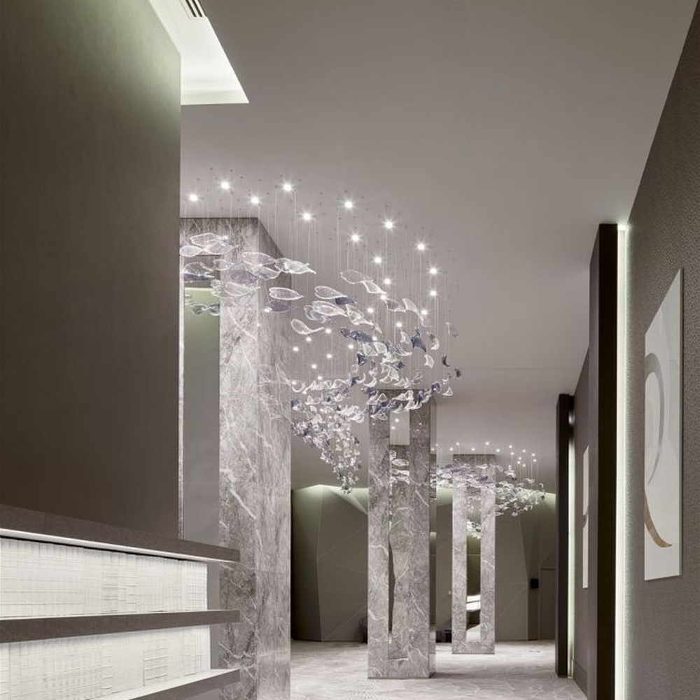 This modern artistic bird-shaped chandelier consists of transparent and gradient blue-purple leaf-shaped glass ornaments hung staggered, arranged in an arc streamline, with point light sources to create a dynamic visual effect, serving both lighting and decorative purposes, suitable for high-end commercial spaces such as luxury sales offices and hotel lobbies.
