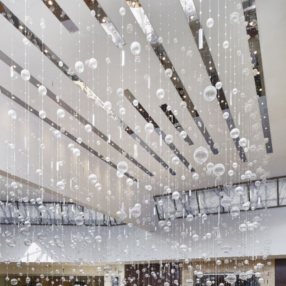 This large artistic bubble chandelier is composed of a large number of transparent glass bubble balls hung in a staggered manner by metal wires, presenting a visual effect like scattered starry sky. The light refracts through the bubbles to emit soft and transparent light spots, serving both lighting and decorative purposes, suitable for high-ceiling commercial spaces such as hotel lobbies and shopping mall atriums.