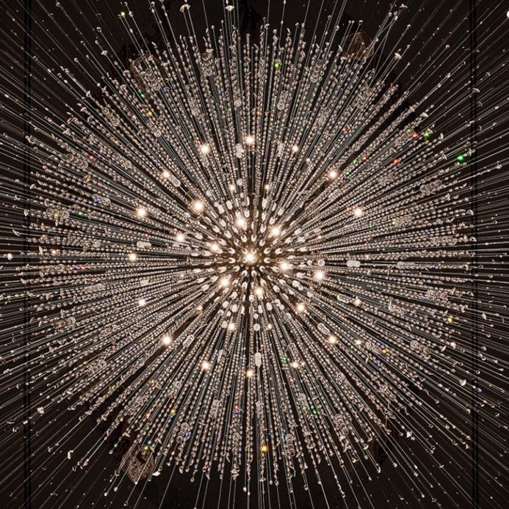 This is a large luxurious starry sky hanging crystal chandelier, supported by a circular metal frame with densely hanging crystal beads, presenting a brilliant starry effect, with both decorative and lighting functions, ideal for high-ceiling commercial spaces such as hotel lobbies and high-end clubs.