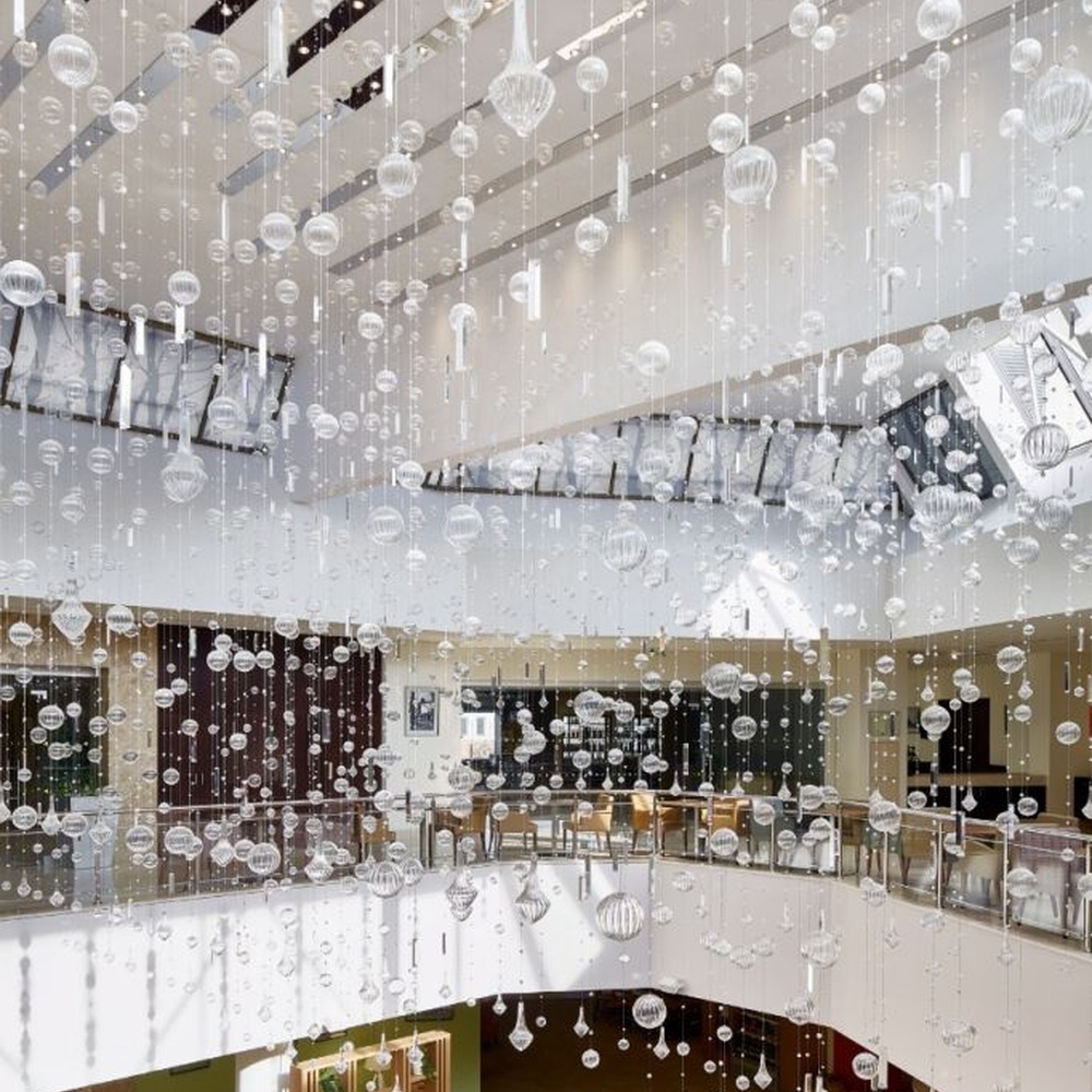 This large artistic bubble chandelier is composed of a large number of transparent glass bubble balls hung in a staggered manner by metal wires, presenting a visual effect like scattered starry sky. The light refracts through the bubbles to emit soft and transparent light spots, serving both lighting and decorative purposes, suitable for high-ceiling commercial spaces such as hotel lobbies and shopping mall atriums.