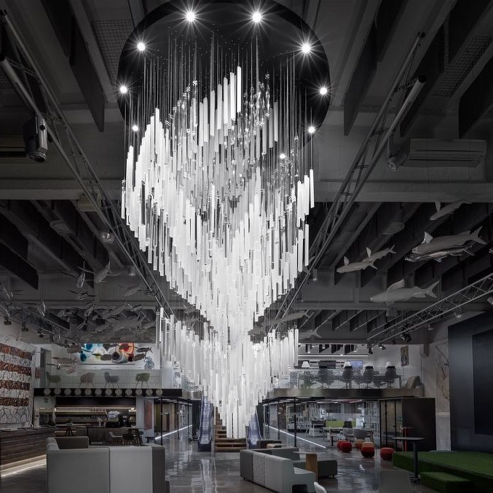 This modern industrial-style art chandelier consists of a large number of white acrylic strips hung staggered by metal wires, extending downward in a waterfall shape from a circular ceiling plate. Light passes through the strips to emit a transparent and soft halo, serving both lighting and decorative purposes, suitable for high-ceiling commercial spaces such as cultural and creative parks and art exhibition halls.