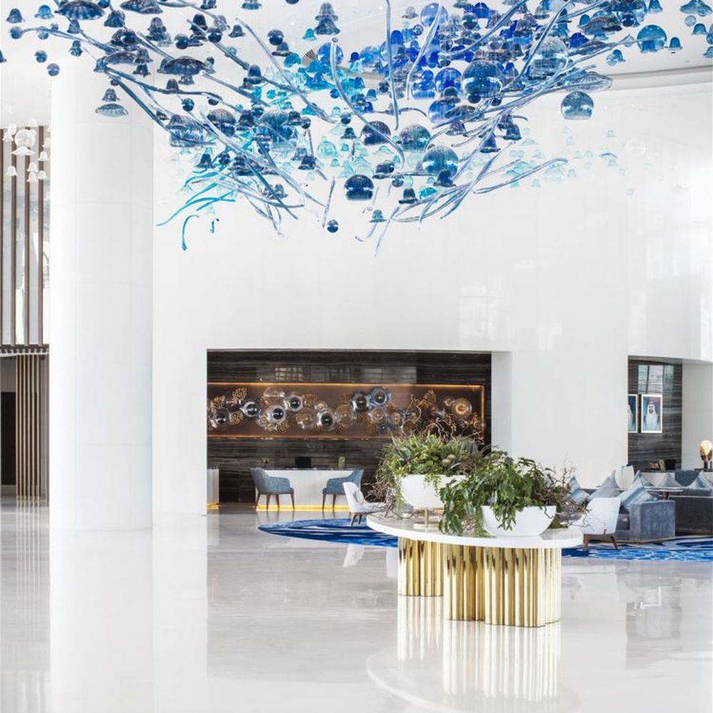 This blue-tone liuli bubble art chandelier is composed of gradient blue and transparent glass bubbles intertwined with metal lines, presenting a dynamic shape like marine plankton. Light refracts through the liuli to emit a transparent and soft halo, serving both lighting and installation art purposes, suitable for high-end commercial spaces such as hotel lobbies and art exhibition halls.