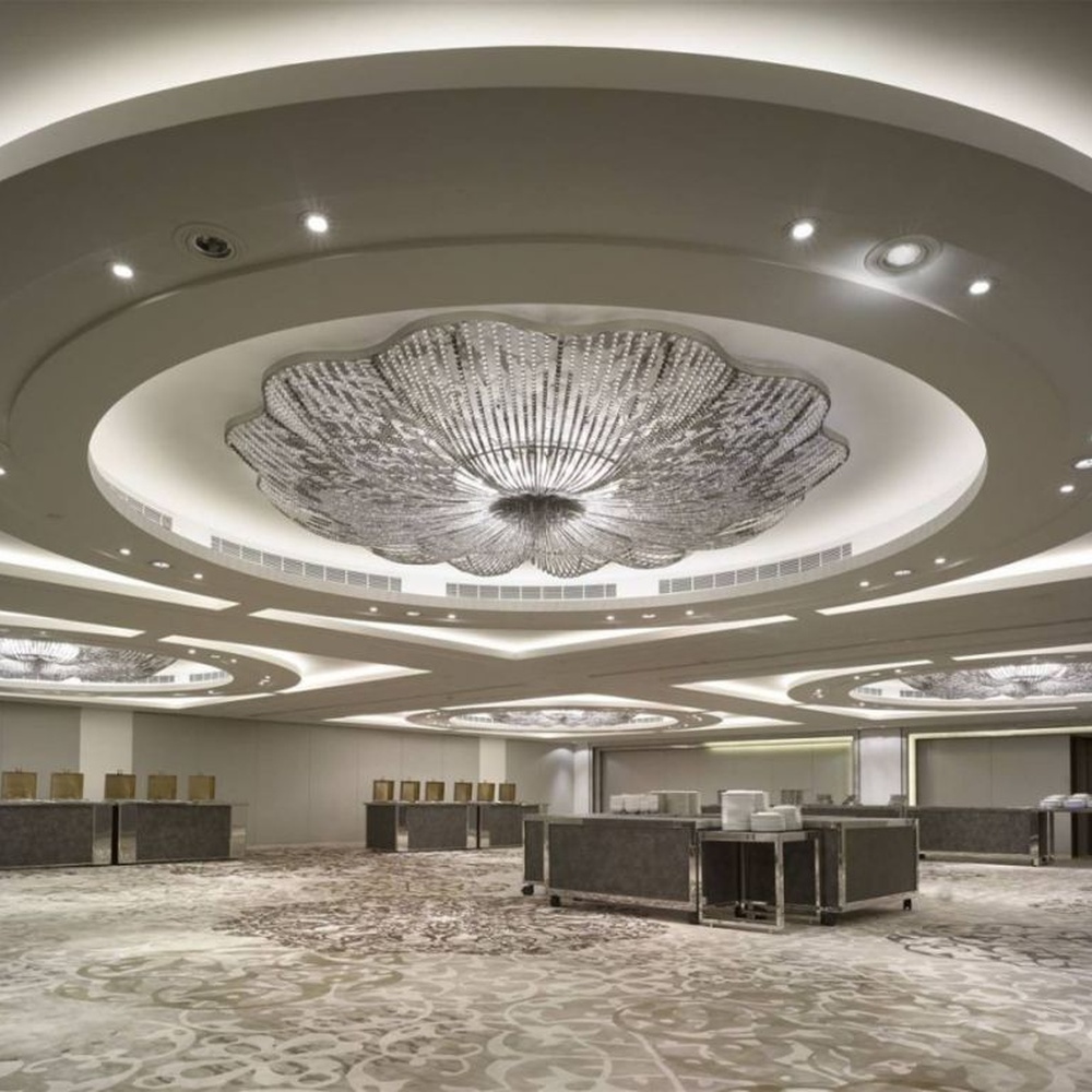 This large petal-shaped crystal ceiling lamp consists of radial crystal strips forming a hollow petal shape, with light refracting a brilliant halo through it, serving both lighting and decorative purposes, suitable for high-end luxury spaces such as hotel banquet halls and large clubs.