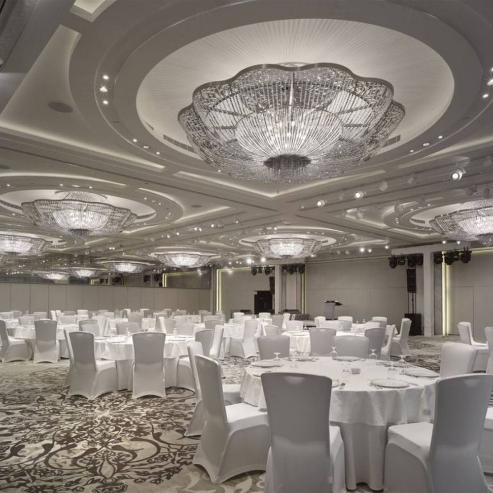 This large petal-shaped crystal ceiling lamp consists of radial crystal strips forming a hollow petal shape, with light refracting a brilliant halo through it, serving both lighting and decorative purposes, suitable for high-end luxury spaces such as hotel banquet halls and large clubs.