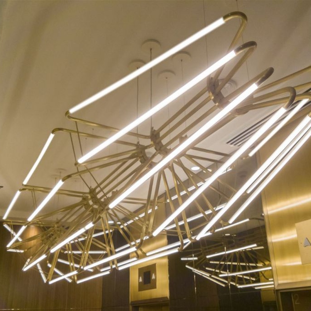 This modern art branch chandelier features an interlaced branch structure made of gold metal, paired with LED strips to form a starburst shape, with soft and visually striking light, serving both lighting and decorative purposes, suitable for high-end modern spaces such as elevator lobbies and clubs.