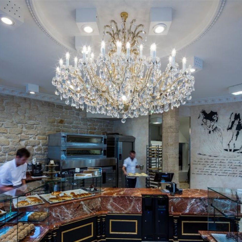 This European court-style multi-layer crystal chandelier features a gold metal frame, paired with faceted crystals and candle-style lamp heads, with light refracting a brilliant halo through the crystals, serving both lighting and decorative purposes, suitable for luxury spaces such as high-end restaurants and clubs.