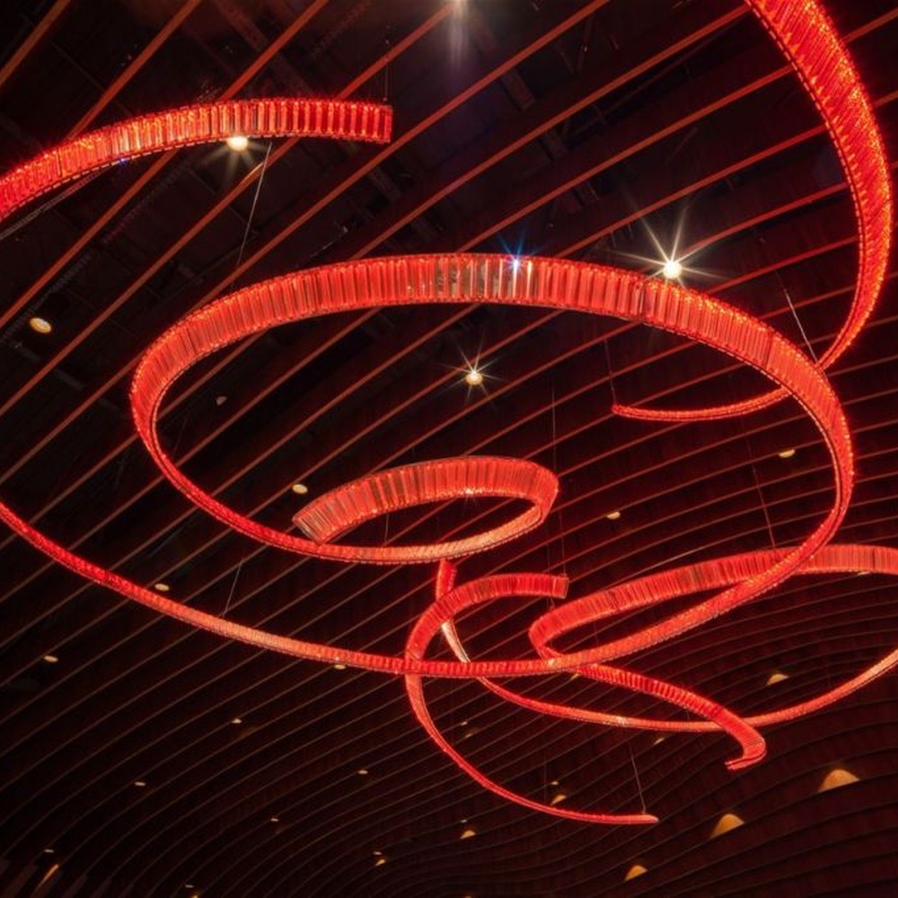 This red spiral crystal art chandelier is composed of red crystal strips spliced into a flowing spiral shape. Light refracts through to emit a brilliant halo, serving both lighting and installation art purposes, suitable for trendy commercial spaces such as bars and clubs.