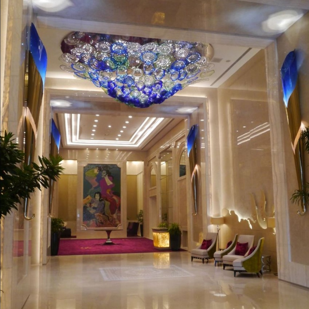 This blue-green gradient liuli bubble art ceiling lamp is composed of layered liuli bubbles forming a cloud shape. Light refracts through to emit a colorful halo, serving both lighting and installation art purposes, suitable for luxury spaces such as hotel lobbies and high-end clubs.