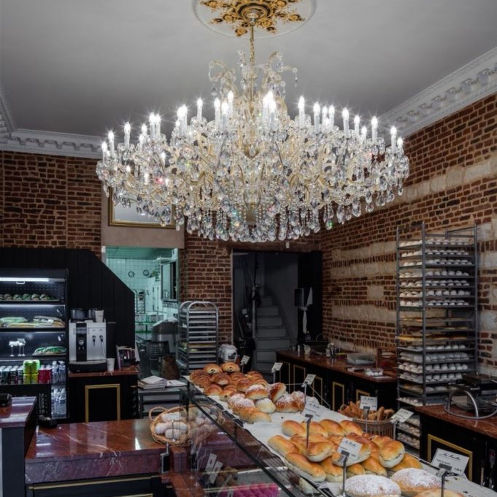 This European court-style multi-layer crystal chandelier features a gold metal frame, paired with faceted crystals and candle-style lamp heads, with light refracting a brilliant halo through the crystals, serving both lighting and decorative purposes, suitable for luxury spaces such as high-end restaurants and clubs.