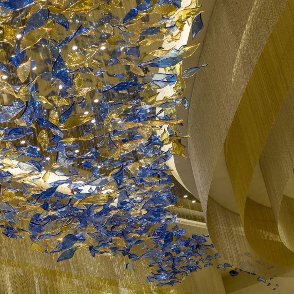 This blue-gold gradient liuli leaf art chandelier is made of liuli leaf-shaped ornaments, layered to create a flowing visual effect. Light refracts through to emit a colorful halo, serving both lighting and installation art purposes, suitable for luxury spaces such as hotel lobbies and high-end clubs.