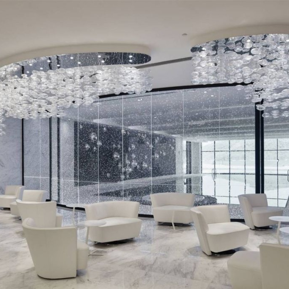 This cloud-like liuli bubble art ceiling lamp is made of transparent liuli bubbles layered into a flowing cloud shape, with light refracting a soft halo through it, serving both lighting and installation art purposes, suitable for modern luxury spaces such as high-end sales offices and clubs.
