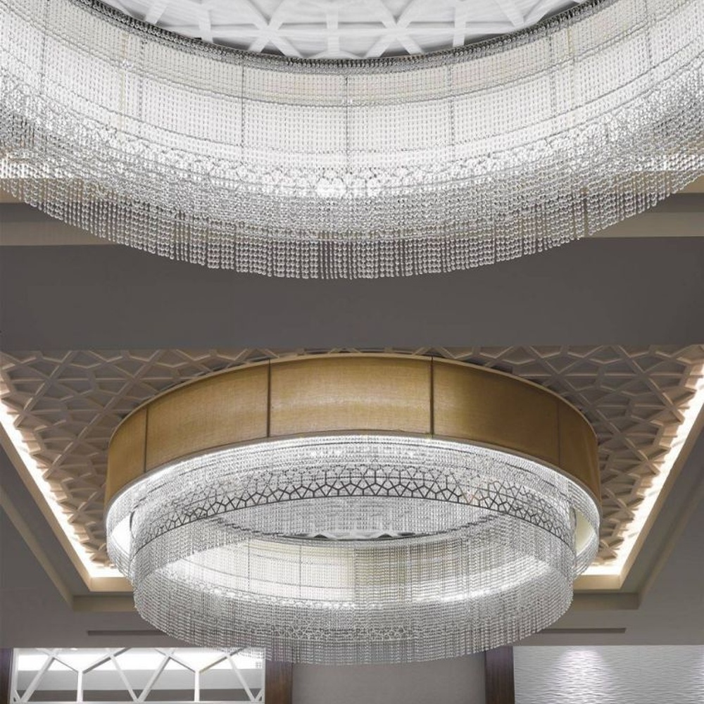 This large multi-layer round crystal ceiling lamp features a gold metal frame paired with multi-layer crystal tassels and a geometric texture lampshade, with light refracting a brilliant halo through the crystals, serving both lighting and decorative purposes, suitable for large high-end commercial spaces such as hotel banquet halls and conference centers.