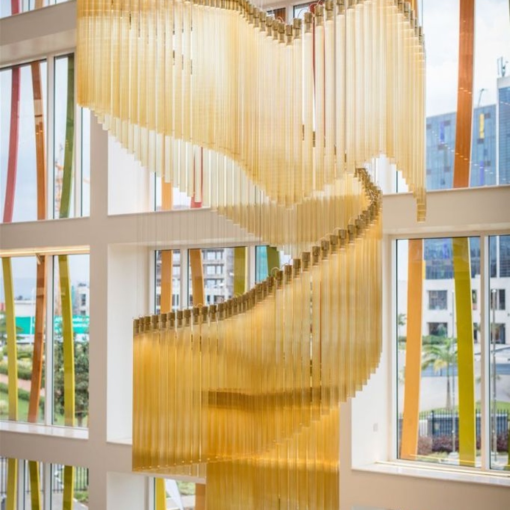 This gilded wave art chandelier is composed of layered gold acrylic strips forming a flowing wave shape, like floating golden ribbons, serving both lighting and installation art purposes, suitable for high-ceiling commercial spaces such as hotel lobbies and convention centers.