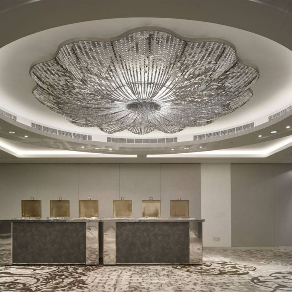 This large petal-shaped crystal ceiling lamp consists of radial crystal strips forming a hollow petal shape, with light refracting a brilliant halo through it, serving both lighting and decorative purposes, suitable for high-end luxury spaces such as hotel banquet halls and large clubs.
