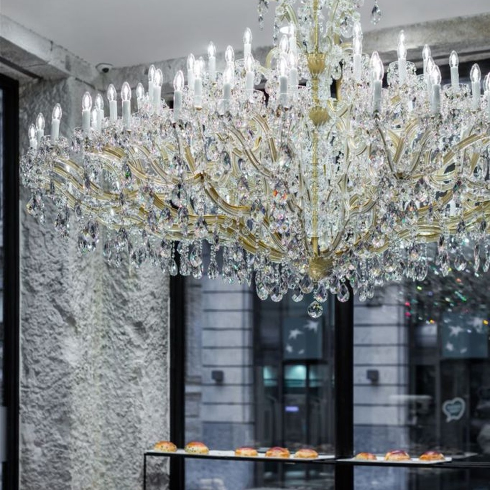 This European court-style multi-layer crystal chandelier features a gold metal frame, paired with faceted crystals and candle-style lamp heads, with light refracting a brilliant halo through the crystals, serving both lighting and decorative purposes, suitable for luxury spaces such as high-end restaurants and clubs.