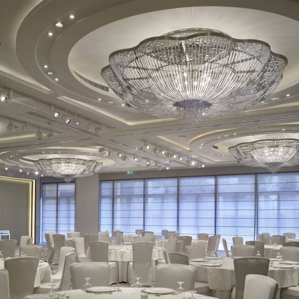 This large petal-shaped crystal ceiling lamp consists of radial crystal strips forming a hollow petal shape, with light refracting a brilliant halo through it, serving both lighting and decorative purposes, suitable for high-end luxury spaces such as hotel banquet halls and large clubs.