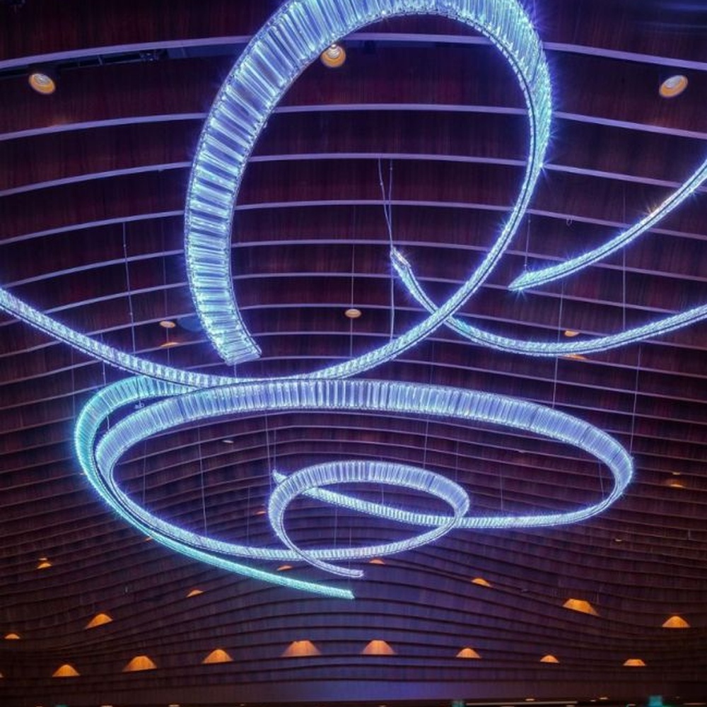 This red spiral crystal art chandelier is composed of red crystal strips spliced into a flowing spiral shape. Light refracts through to emit a brilliant halo, serving both lighting and installation art purposes, suitable for trendy commercial spaces such as bars and clubs.