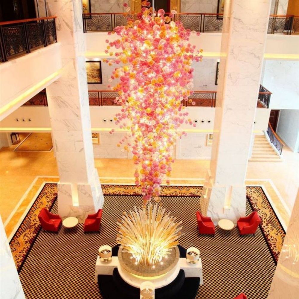 Modern artistic flower cluster-shaped hanging chandelier, with pink-orange gradient crystal/acrylic petals stacked into a full flower cluster shape, combining artistic decoration and main lighting functions, suitable for high-ceiling large-scale spaces such as hotel lobbies, high-end clubs, and commercial atriums.
