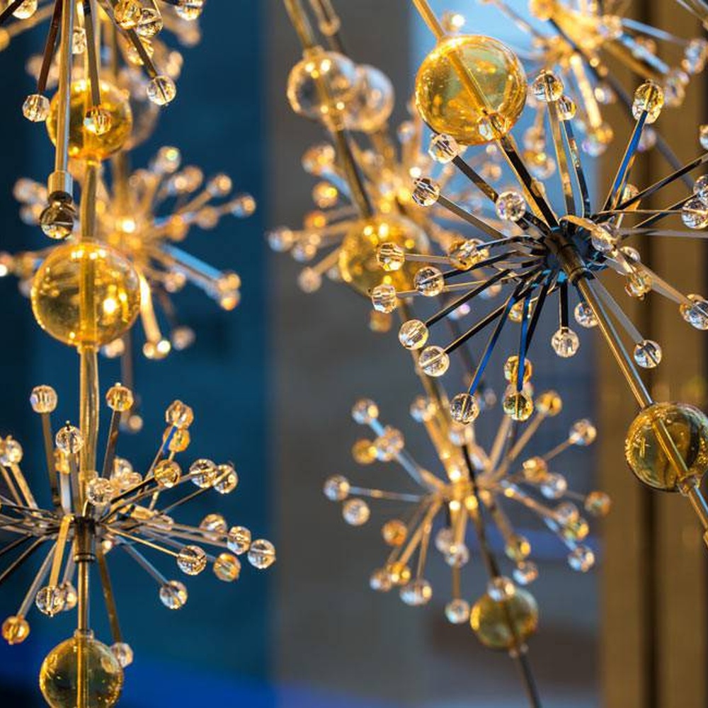 Modern artistic dandelion-shaped chandelier, with metal branches and crystal/glass particles creating a radial spherical structure, featuring bright and soft light, combining decorative and lighting functions, suitable for living rooms, dining rooms, high-end clubs and other modern art style spaces.