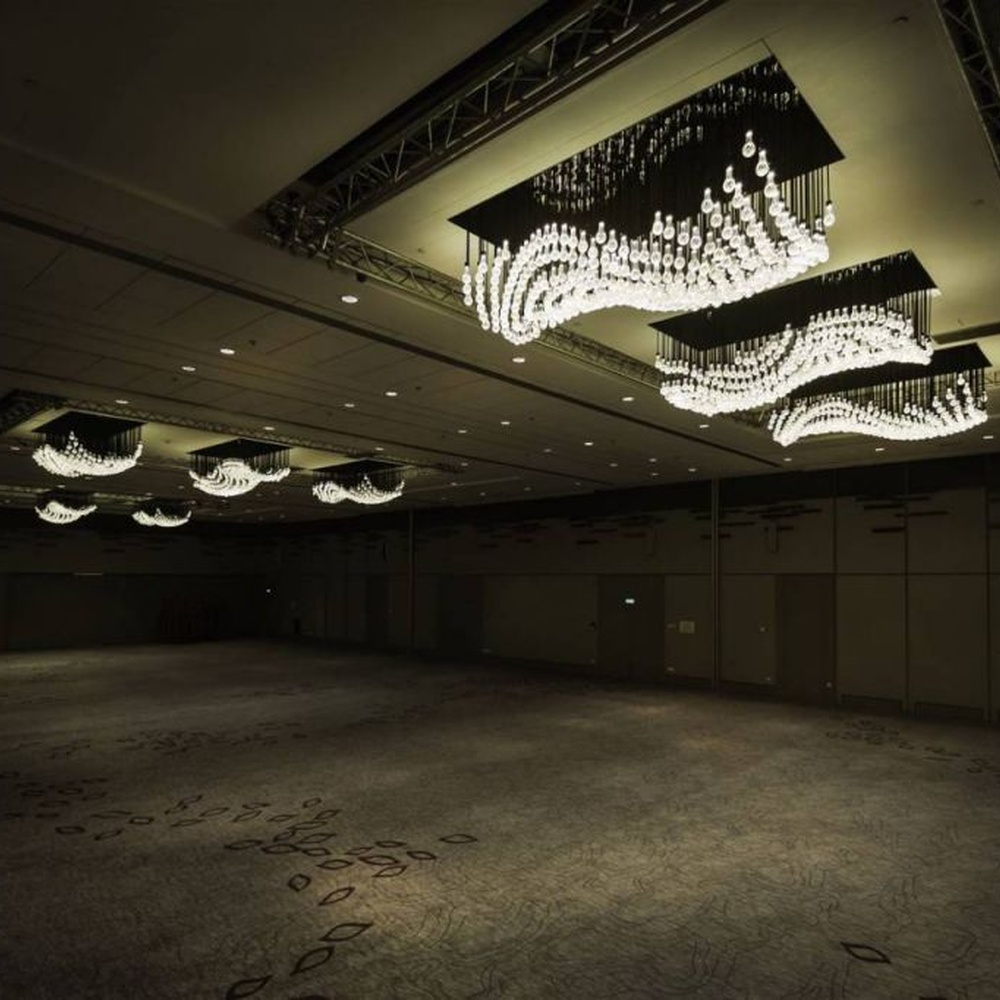 Modern artistic wavy hanging crystal chandelier, with a black metal frame and dense crystal particles creating a flowing wavy shape, combining decorative and main lighting functions, suitable for large-scale commercial spaces such as large banquet halls, exhibition centers, and high-end clubs.