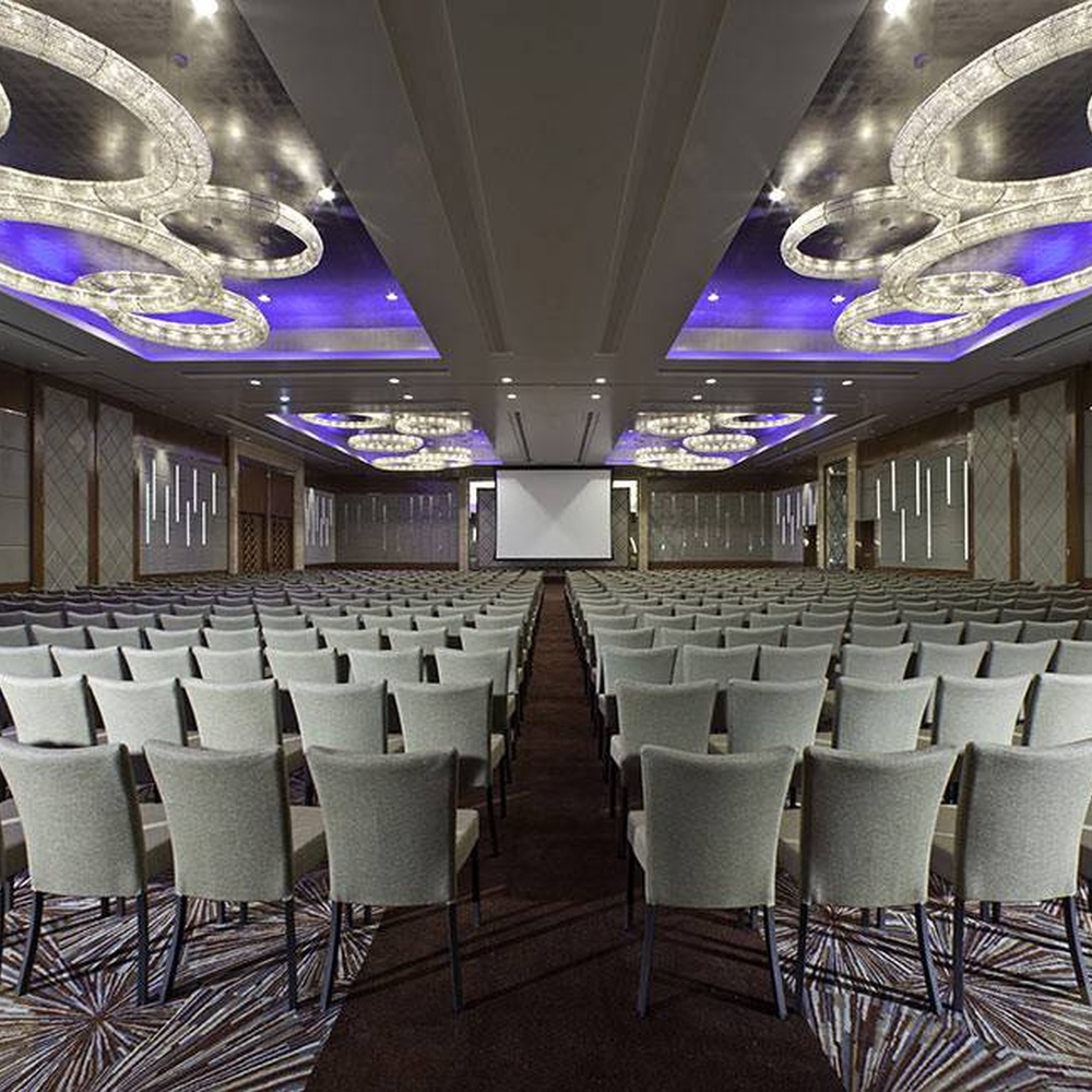 Modern light luxury ring-shaped crystal combination lamp, composed of multiple groups of ring-shaped crystal lamp bodies of different sizes embedded in the ceiling, paired with purple ambient light strips, combining main lighting and atmosphere creation functions, suitable for high-end commercial spaces such as hotel banquet halls and large conference halls.