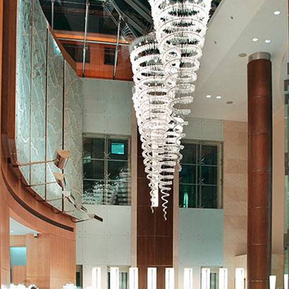 Modern luxury spiral crystal chandelier, made of stacked crystal strips and metal structure to create a suspended tornado shape with strong visual impact. It combines artistic decoration and main lighting functions, suitable for hotel lobbies, high-end clubs, high-ceiling office spaces and other venues.