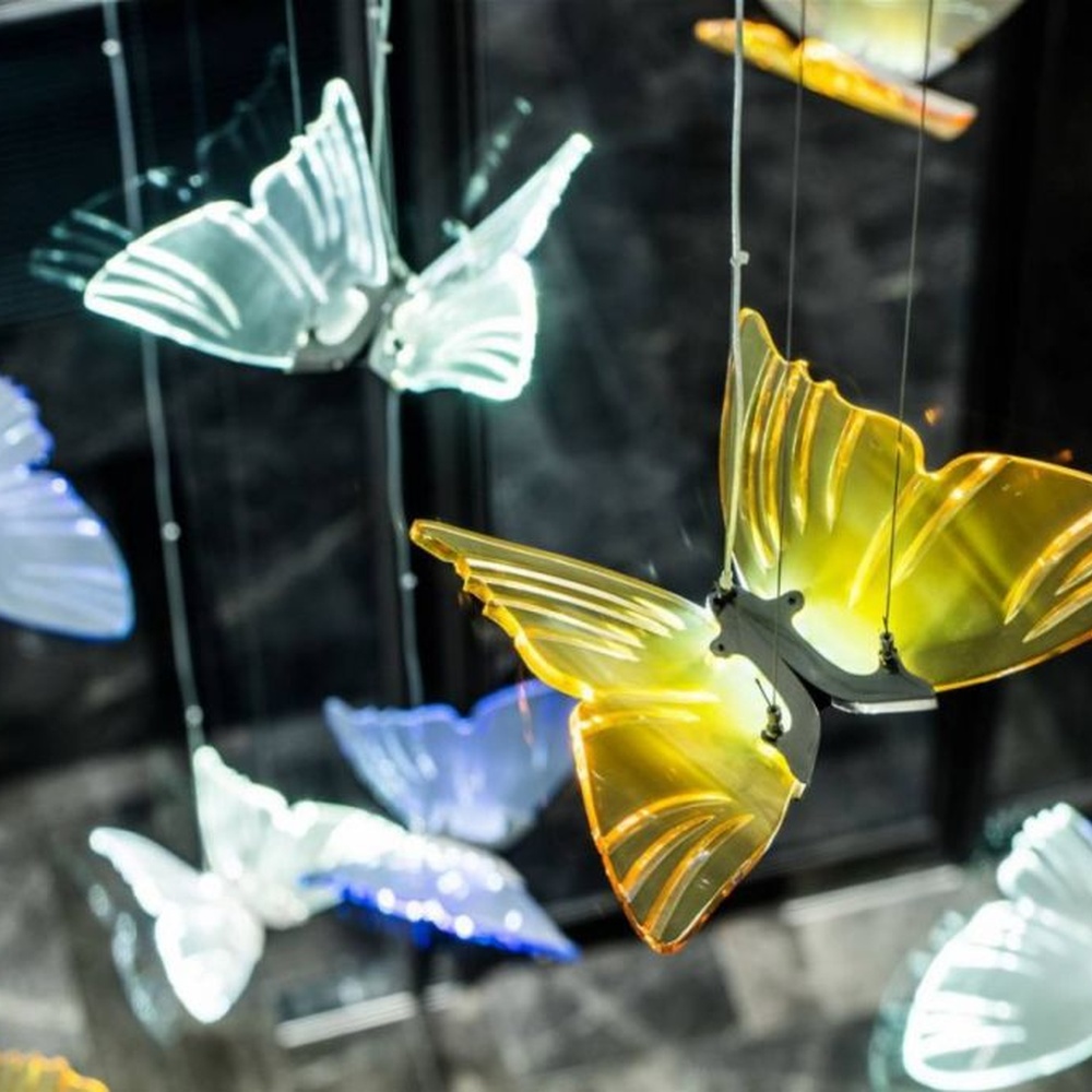 Modern artistic butterfly-shaped suspended chandelier, made of colored glass/acrylic to create a realistic butterfly form, paired with adjustable metal suspension rods, combining decorative and ambient lighting functions, suitable for hotel lobbies, high-end clubs, art exhibition halls and other spaces.