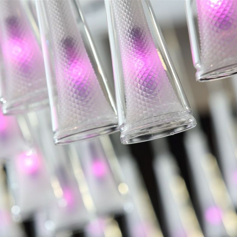 This modern gradient cone LED chandelier features transparent conical lampshades paired with LED gradient pink-purple light sources, arranged in a staggered drooping manner with slender suspension rods, with soft and dreamy light, serving both lighting and decorative purposes, suitable for modern entertainment commercial spaces such as bars and lounges.