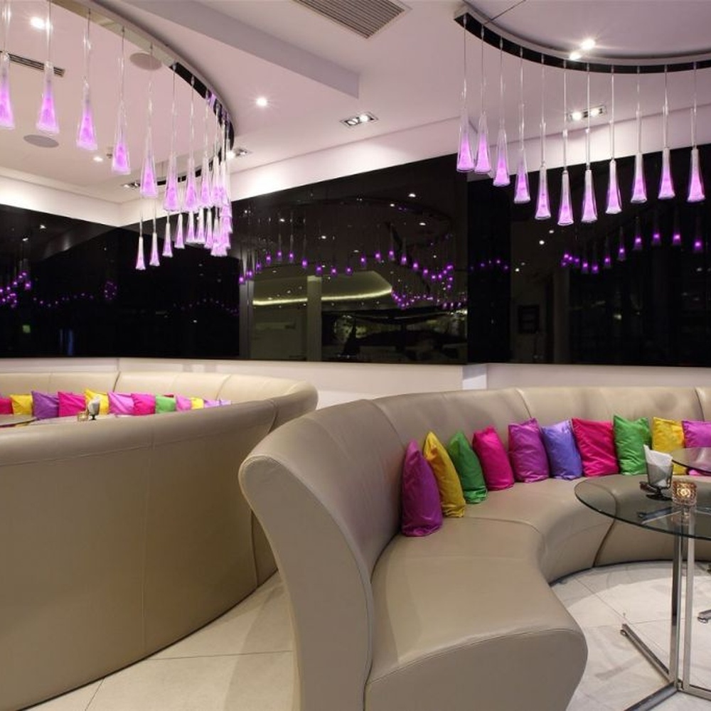 This modern gradient cone LED chandelier features transparent conical lampshades paired with LED gradient pink-purple light sources, arranged in a staggered drooping manner with slender suspension rods, with soft and dreamy light, serving both lighting and decorative purposes, suitable for modern entertainment commercial spaces such as bars and lounges.