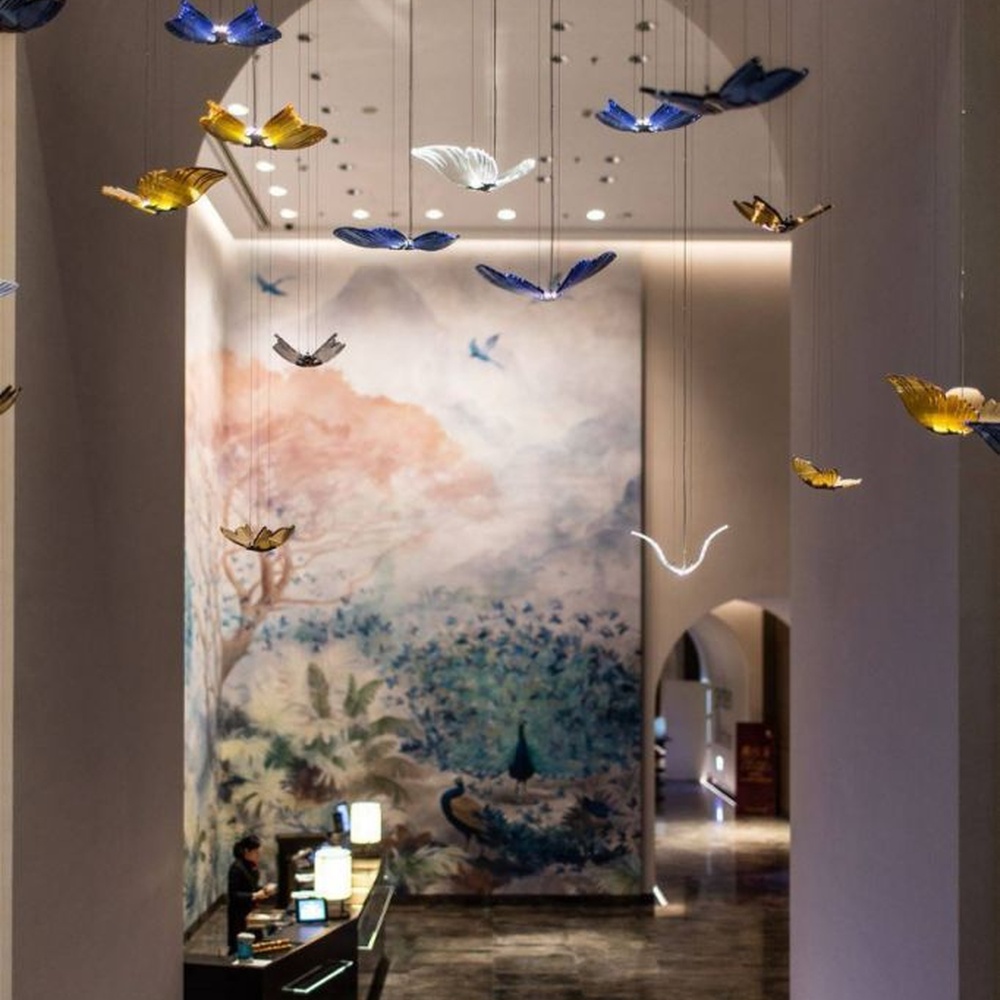 Modern artistic butterfly-shaped suspended chandelier, made of colored glass/acrylic to create a realistic butterfly form, paired with adjustable metal suspension rods, combining decorative and ambient lighting functions, suitable for hotel lobbies, high-end clubs, art exhibition halls and other spaces.