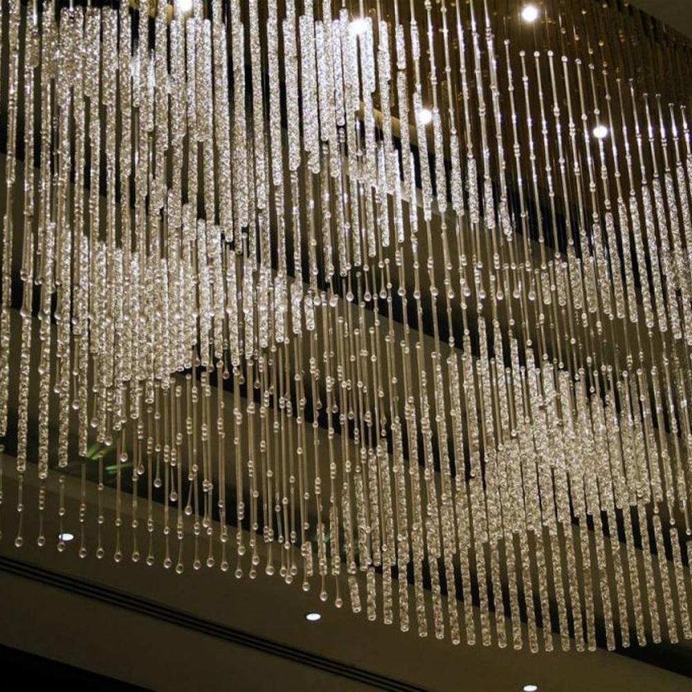 Modern luxury linear hanging crystal lamp group, made of dense crystal strips and particles stacked to create a flowing light belt shape, combining decorative and lighting functions, suitable for large-scale commercial spaces such as hotel lobbies, high-end clubs, and commercial atriums.
