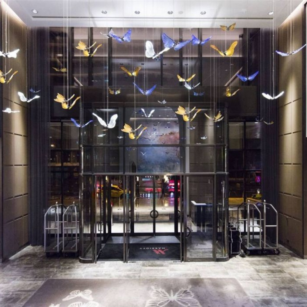 Modern artistic butterfly-shaped suspended chandelier, made of colored glass/acrylic to create a realistic butterfly form, paired with adjustable metal suspension rods, combining decorative and ambient lighting functions, suitable for hotel lobbies, high-end clubs, art exhibition halls and other spaces.