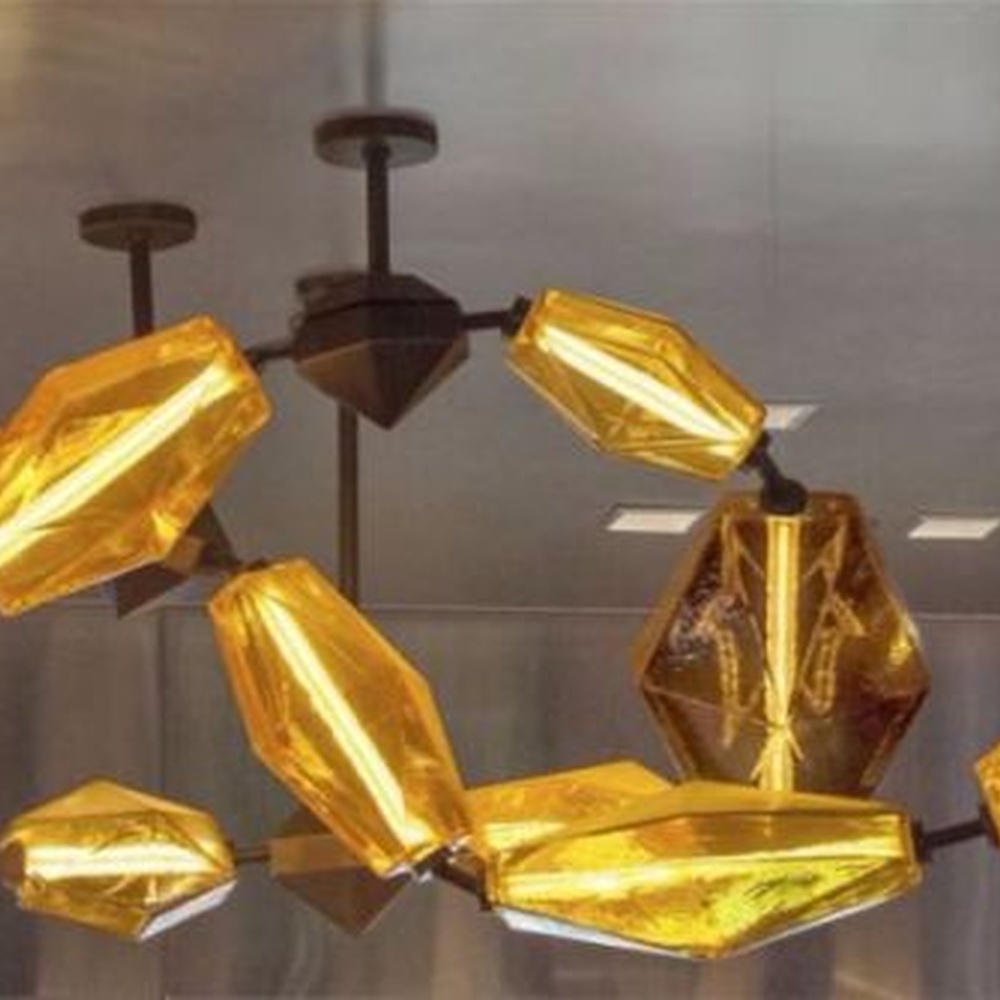 This modern art liuli chandelier features black metal brackets connecting irregular golden liuli leaves, with transparent and soft light, serving both lighting and decorative purposes, suitable for modern entertainment commercial spaces such as bars and high-end clubs.