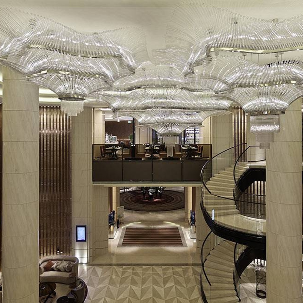 This large wave-shaped crystal ceiling lamp consists of dense high-transparency crystal strips forming a flowing wave pattern, covering the entire ceiling, with soft and brilliant light, serving both lighting and installation art purposes, suitable for large high-ceiling spaces such as hotel lobbies and high-end commercial atriums.