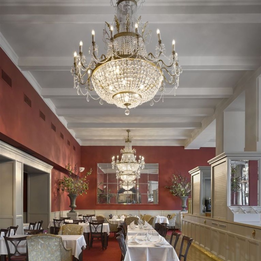 This European court-style multi-layer crystal chandelier features a gold metal frame paired with dense faceted crystals and candle-shaped lamp heads, with light refracting a brilliant halo through the crystals, serving both lighting and decorative purposes, suitable for luxury spaces such as high-end restaurants and hotel lobbies.