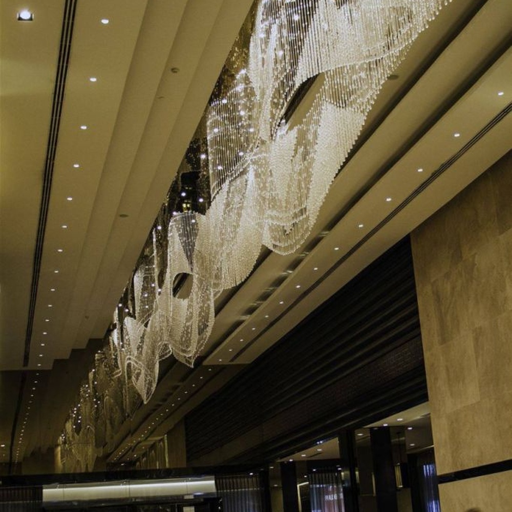 Modern luxury linear hanging crystal lamp group, made of dense crystal strips and particles stacked to create a flowing light belt shape, combining decorative and lighting functions, suitable for large-scale commercial spaces such as hotel lobbies, high-end clubs, and commercial atriums.