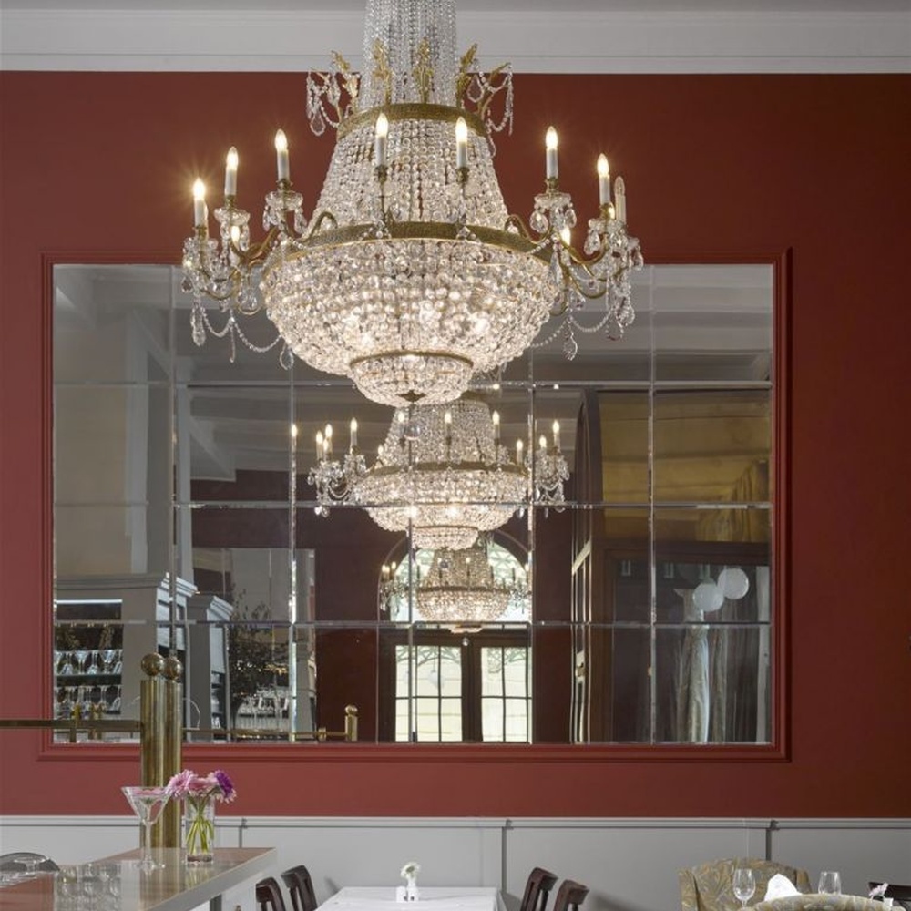 This European court-style multi-layer crystal chandelier features a gold metal frame paired with dense faceted crystals and candle-shaped lamp heads, with light refracting a brilliant halo through the crystals, serving both lighting and decorative purposes, suitable for luxury spaces such as high-end restaurants and hotel lobbies.