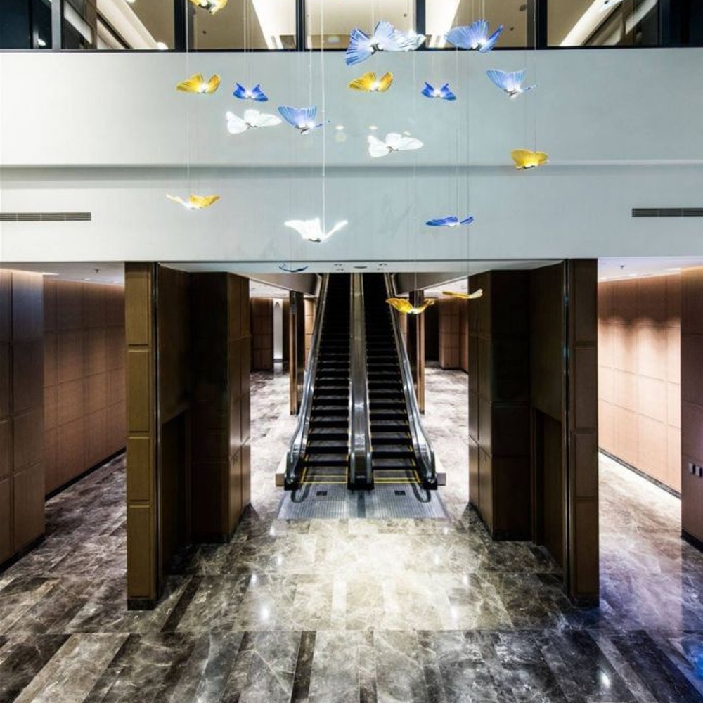 Modern artistic butterfly-shaped suspended chandelier, made of colored glass/acrylic to create a realistic butterfly form, paired with adjustable metal suspension rods, combining decorative and ambient lighting functions, suitable for hotel lobbies, high-end clubs, art exhibition halls and other spaces.